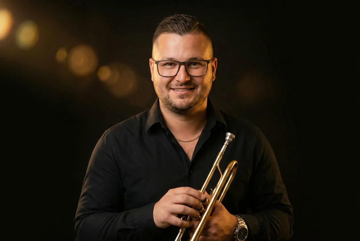 Jakub Košíček Grufík s trumpetou v černém obleku a bílých teniskách